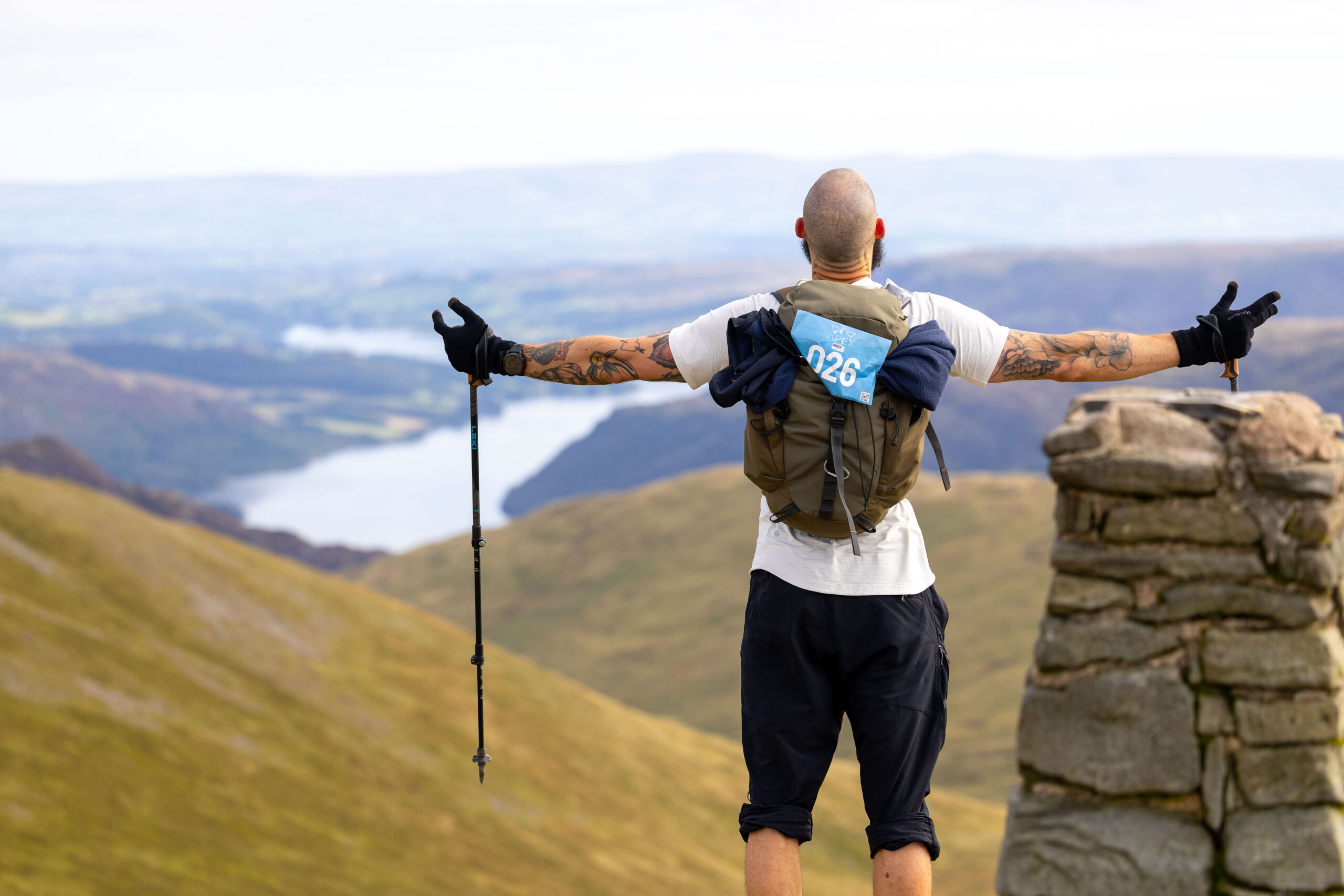 Man standing with arms out to the side on top hill in lake district at APEX everest event.